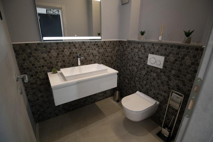 Luxus fürdőszoba sötét kavicsos falakkal és modern bútorokkal az isztriai Labinban található villában.