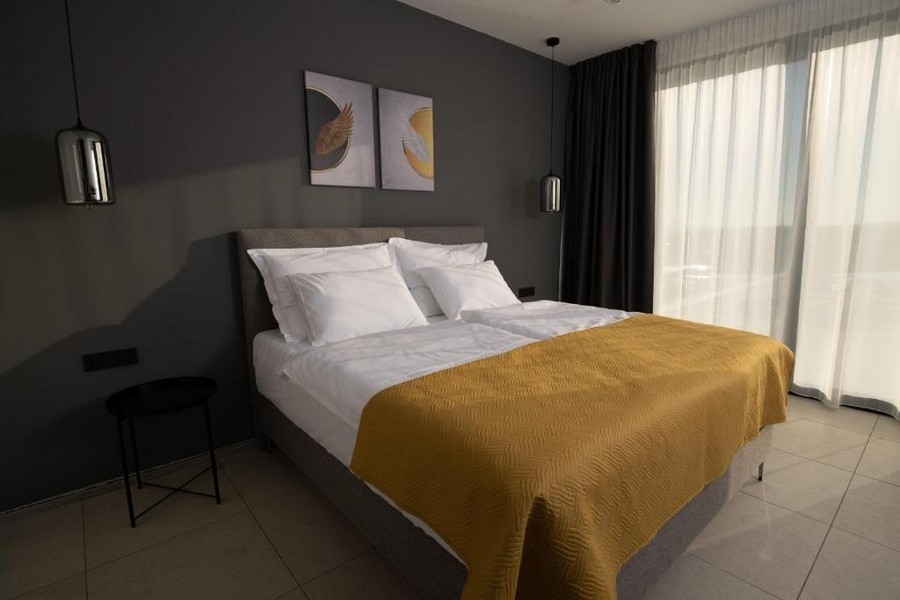 Exkluzív villa kilátással a medencére és a tengerre Labinban, Isztria - Világos hálószoba sárga paplannal és műalkotásokkal a falon