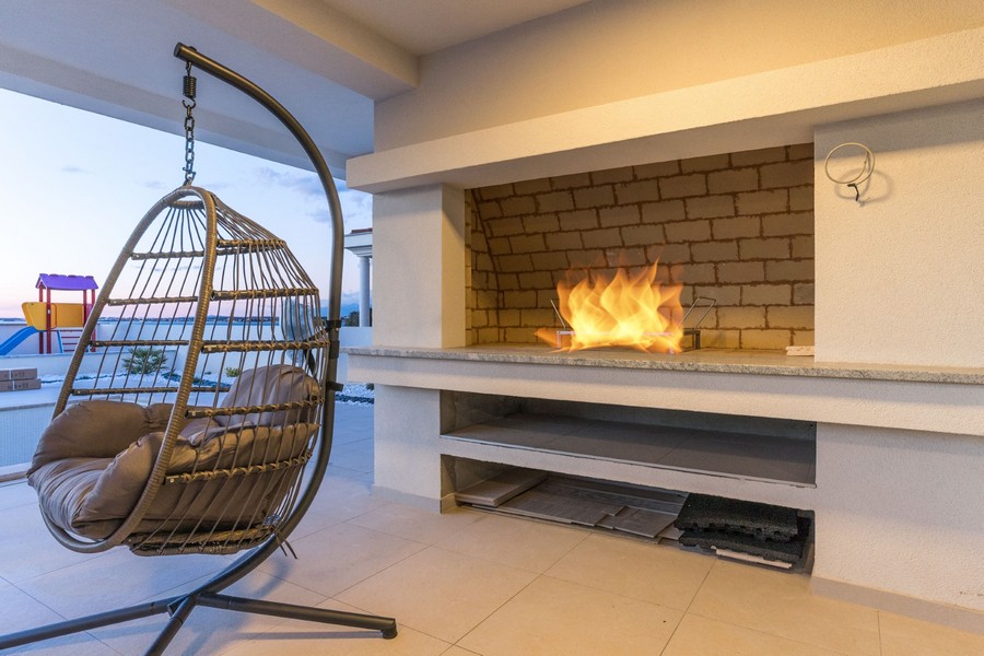 Modern luxusvilla függőszékkel és beépített kandallóval, tökéletes egy hangulatos estéhez új horvátországi ingatlanában.
