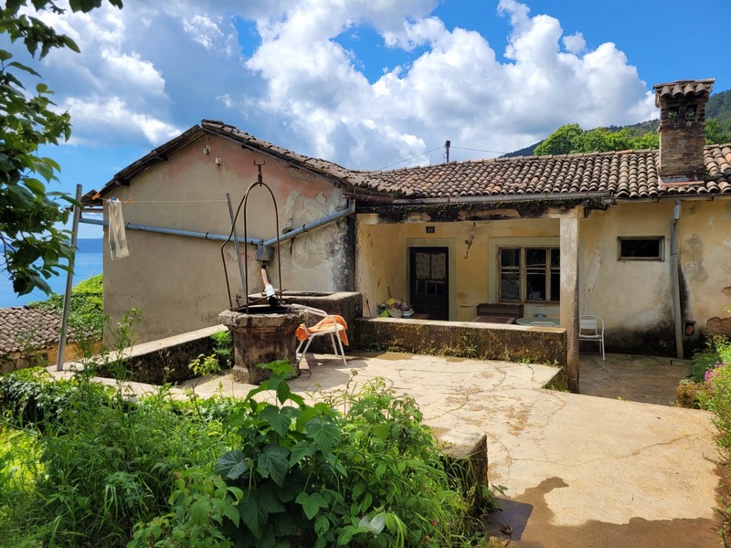 Közeli kép egy rusztikus kőházról egy régi kúttal, amely egy elbűvölő horvátországi ingatlant mutat be, amely felújítható.