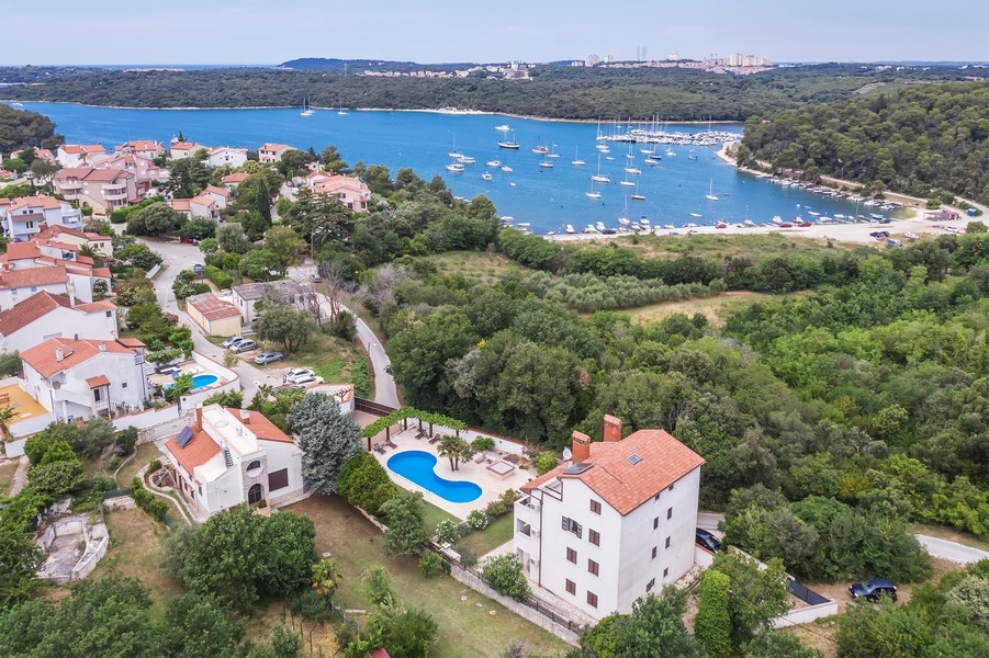 Horvátországi ingatlan, tengerre néző bérház Isztrián - Panorama Scouting H3025: A légi felvételen egy festői tengerparti város látható, több házzal és csónakkal a vízben