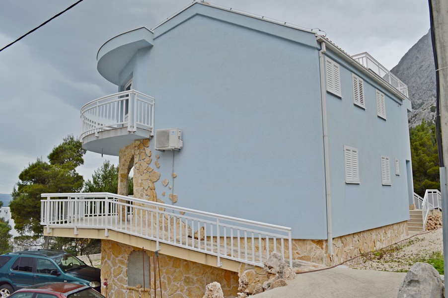 Kék ház kőfallal és erkéllyel