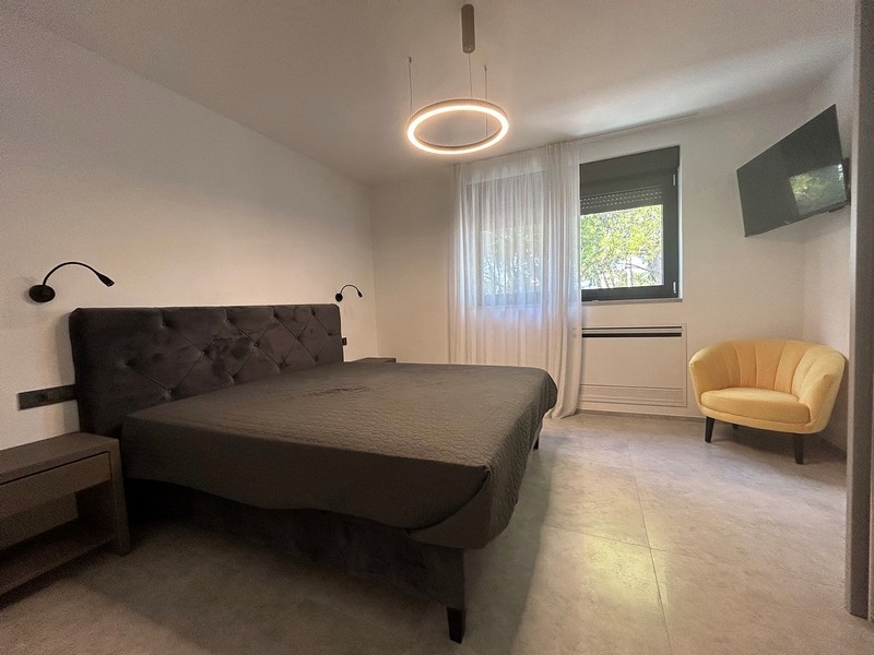 Hangulatos hálószoba fotellel és nagy ablakkal, amely sok természetes fényt enged be