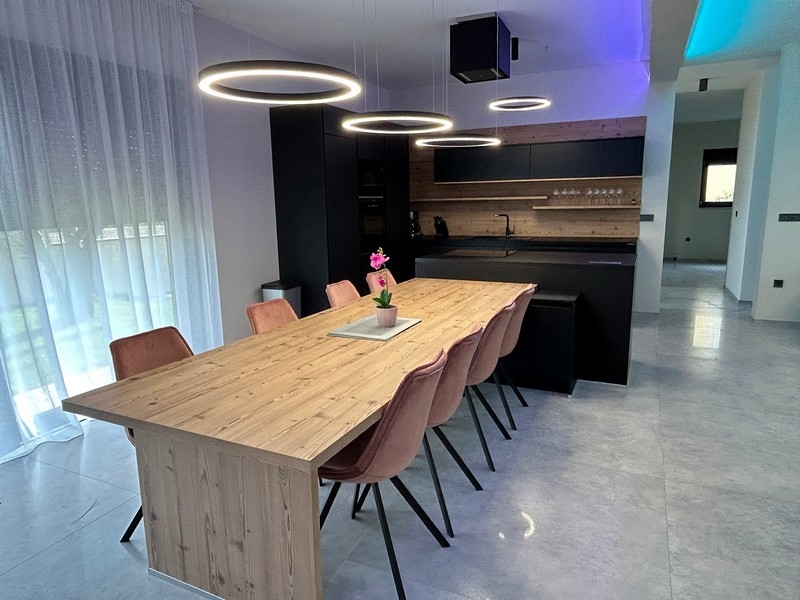 A villa modern konyhája és étkezője stílusos világítással és fából készült asztallal