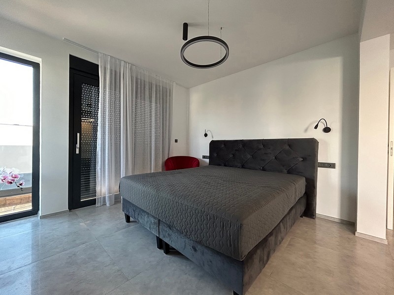 A minimalista bútorokkal berendezett hálószoba közvetlen teraszkapcsolattal rendelkezik