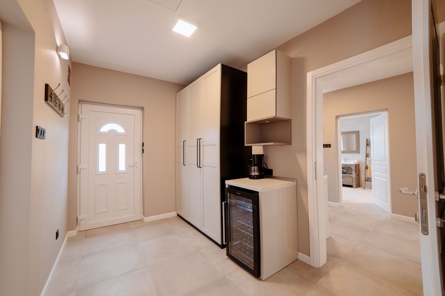 Bejárati rész modern szekrényekkel, borhűtővel és kilátással az elegáns fürdőszobába