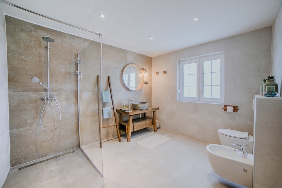 Luxus fürdőszoba nagy zuhanykabinnal, bidével és rusztikus fa mosdóval, földszínekkel és modern berendezéssel