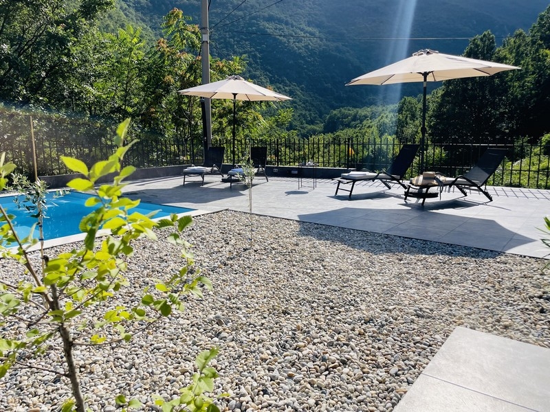 Napozóterasz a medence mellett napozóágyakkal és napernyőkkel, zöld természettel körülvéve