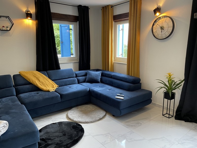 Kiváló minőségű kék ​​kanapé és gyönyörű csempézett padló a nappaliban.