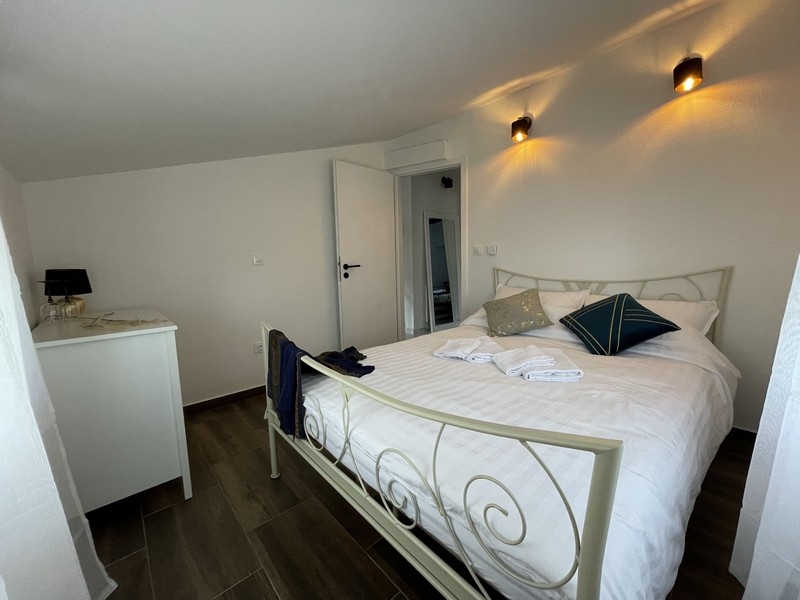 Hálószoba fehér kovácsoltvas ággyal, dekoratív párnákkal és modern hangulattal