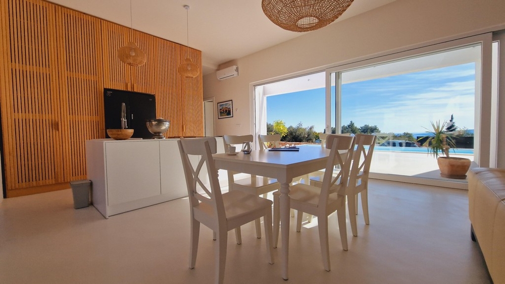 Nyitott nappali és étkező, kilátással a horvátországi Krk-i villa teraszára és medencéjére.