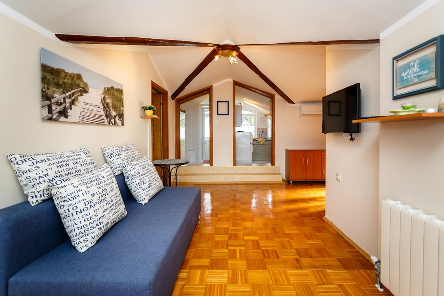 A nappali kanapéval, fapadlóval és gerendás mennyezettel egy kis konyhába vezet