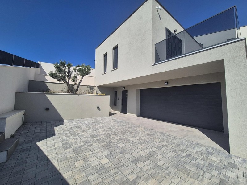 Kilátás a teraszról a tengerre és a környező házakra, modern épület oszlopokkal és üvegkorlátokkal