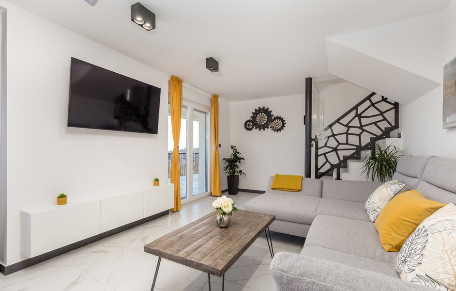 Modern nappali szürke kanapéval és sárga díszítéssel