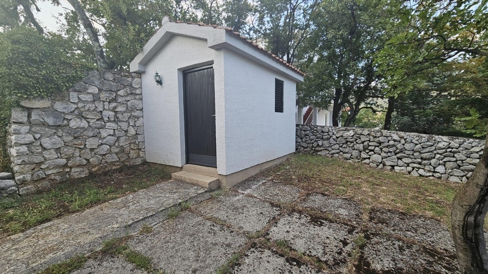 A kertben kis melléképület kőfallal