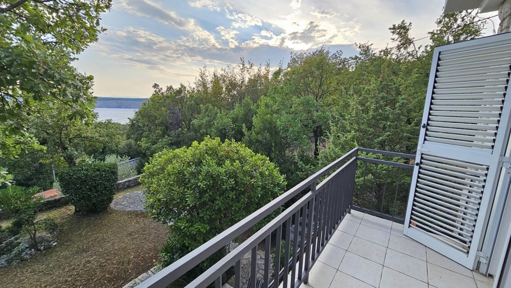 Erkély, kilátással a fákra és a tengerre a háttérben