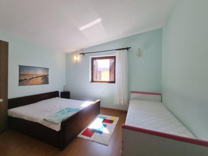 A hálószoba franciaággyal és egy egyszemélyes ággyal, világos falakkal és természetes fényű ablakokkal rendelkezik.