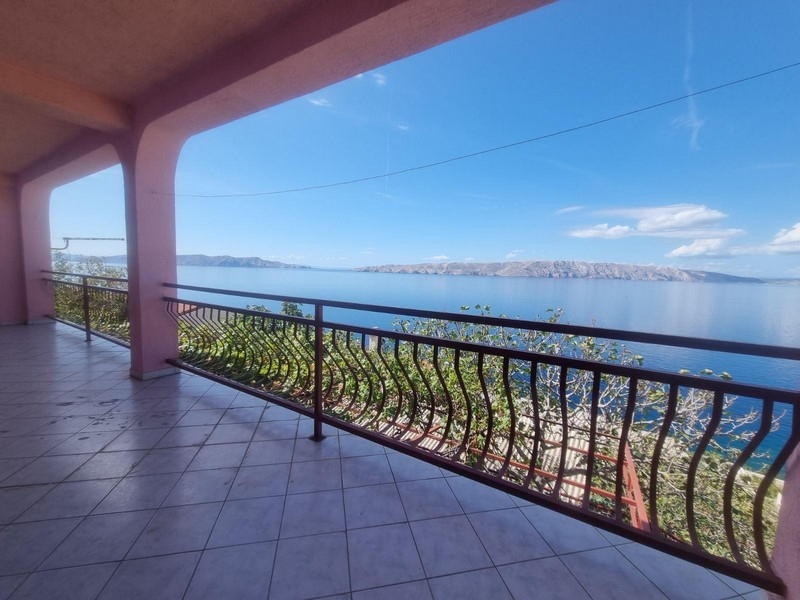 Tágas, tengerre néző terasz íves korlátokkal, fedett terület alatt.