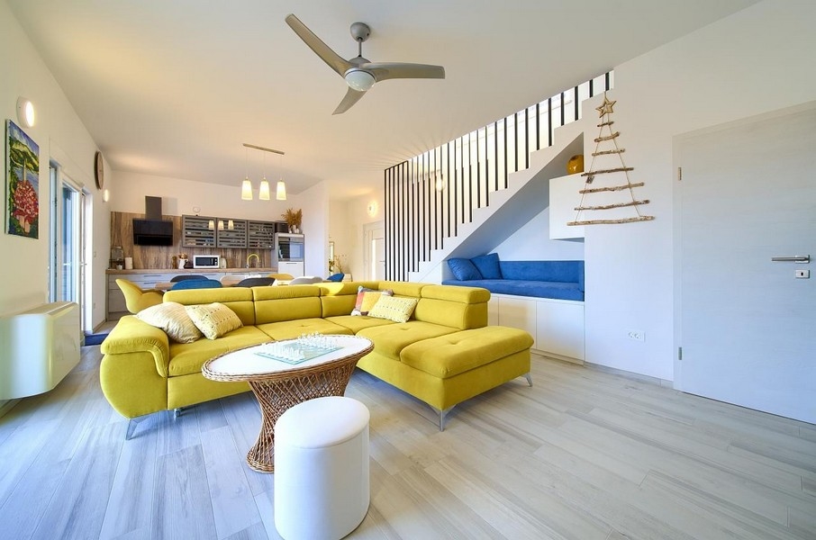 Nagy nappali sárga kanapéval, beépített étkezővel és konyhával, nyitott, modern kialakítással