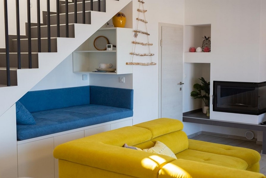Nappali sárga kanapéval, kék ülőrésszel a lépcső alatt, modern dizájnnal