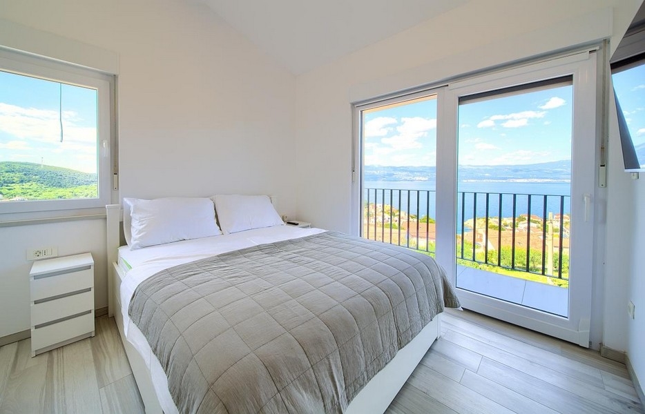Hálószoba franciaággyal és erkélyajtókkal, a háttérben csodálatos kilátás nyílik a tengerre
