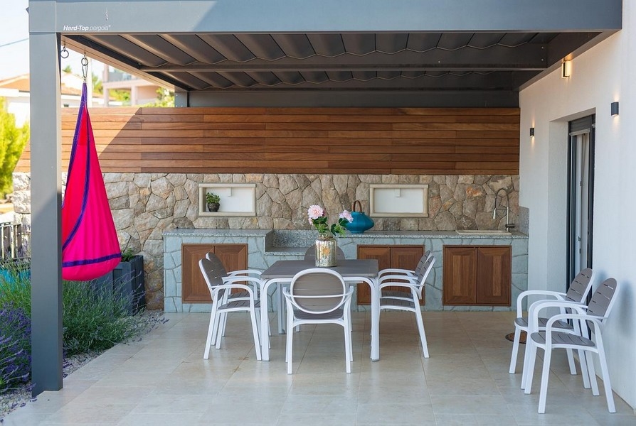 Szabadtéri étkező és kő konyha nappali fényben, függőággyal