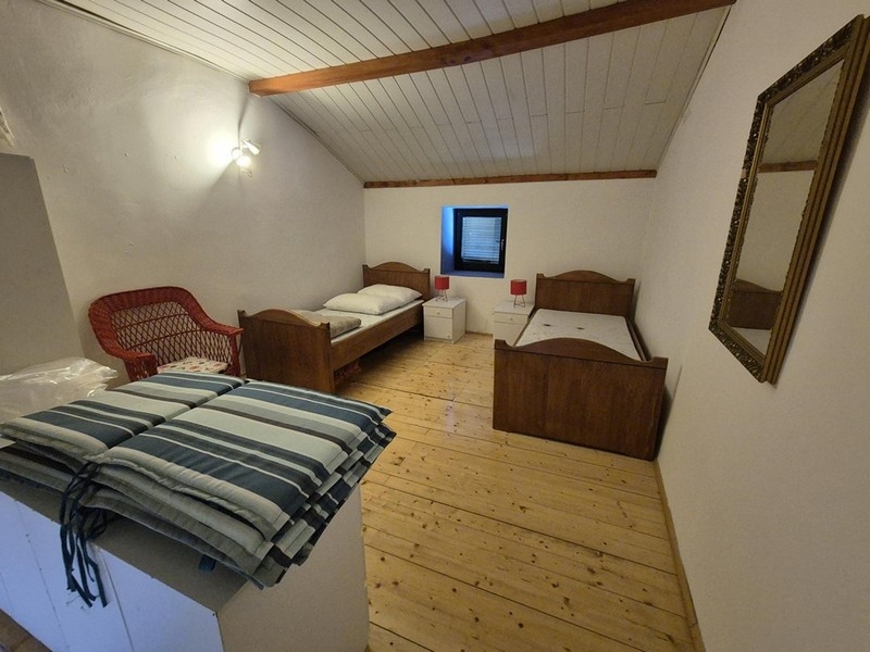 Hálószoba két egyszemélyes ággyal és egyszerű bútorokkal.