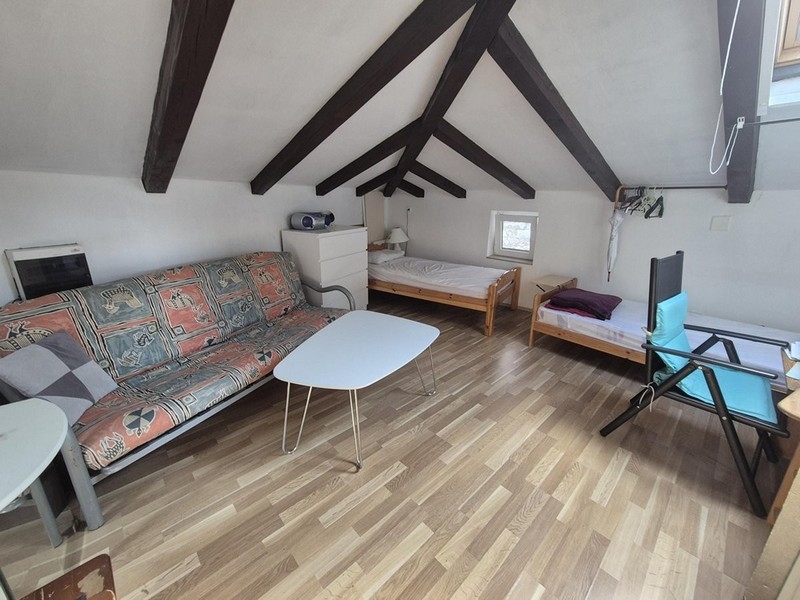 A tetőtérben nyitott terű lakótér két ággyal és fagerendás mennyezettel.