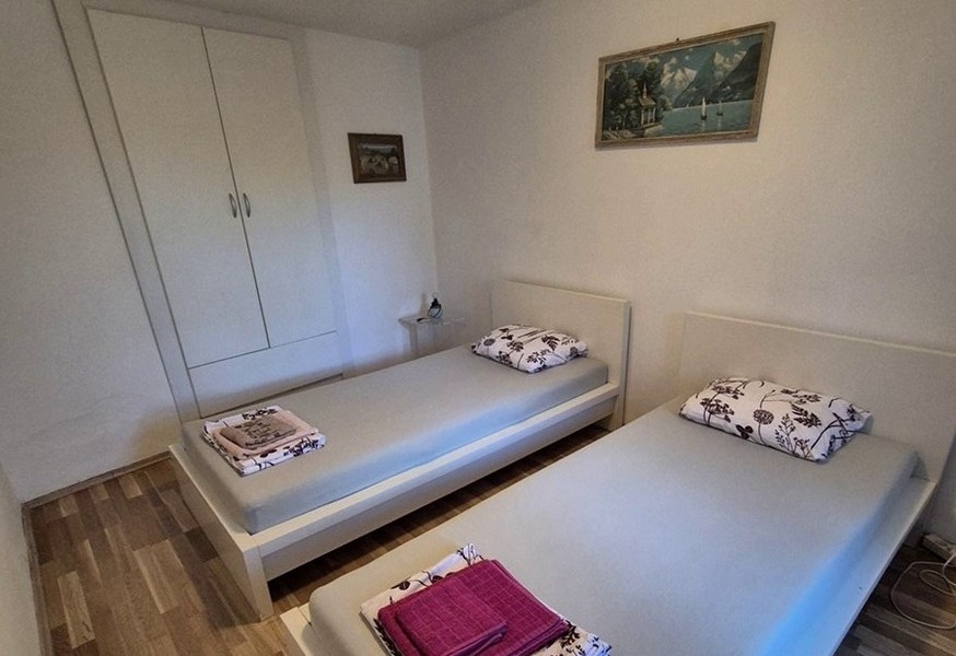 Hálószoba két egyszemélyes ággyal és egyszerű bútorokkal.