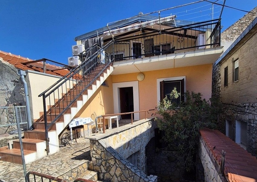 A mediterrán kőház hátulnézete külső lépcsőkkel és terasszal.