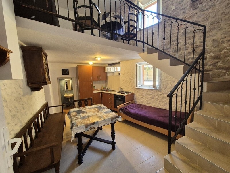 Rusztikus stílusú nappali fagerendákkal és kőlépcsőkkel.