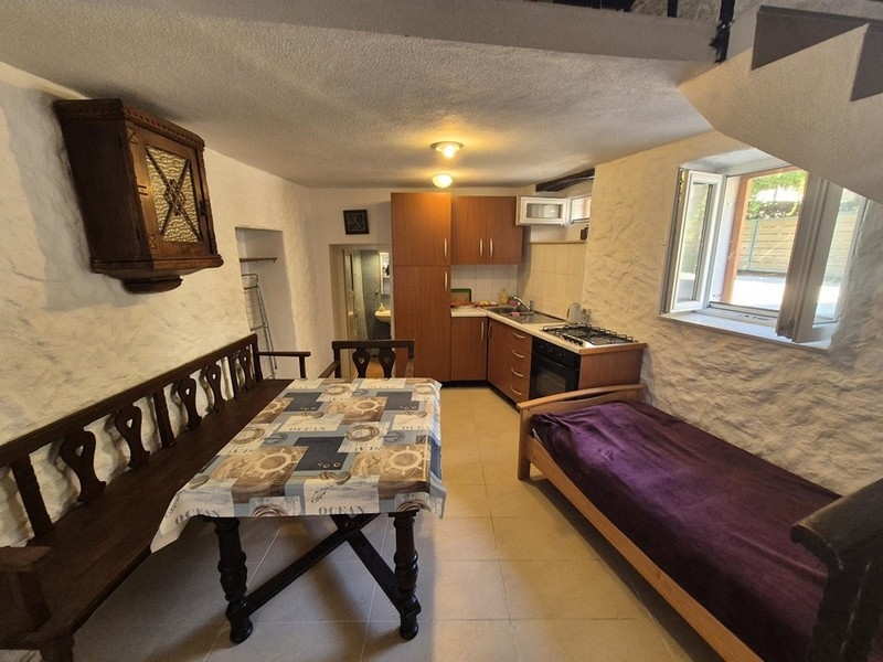 Rusztikus bútorokkal berendezett étkező és konyha a ház földszintjén.