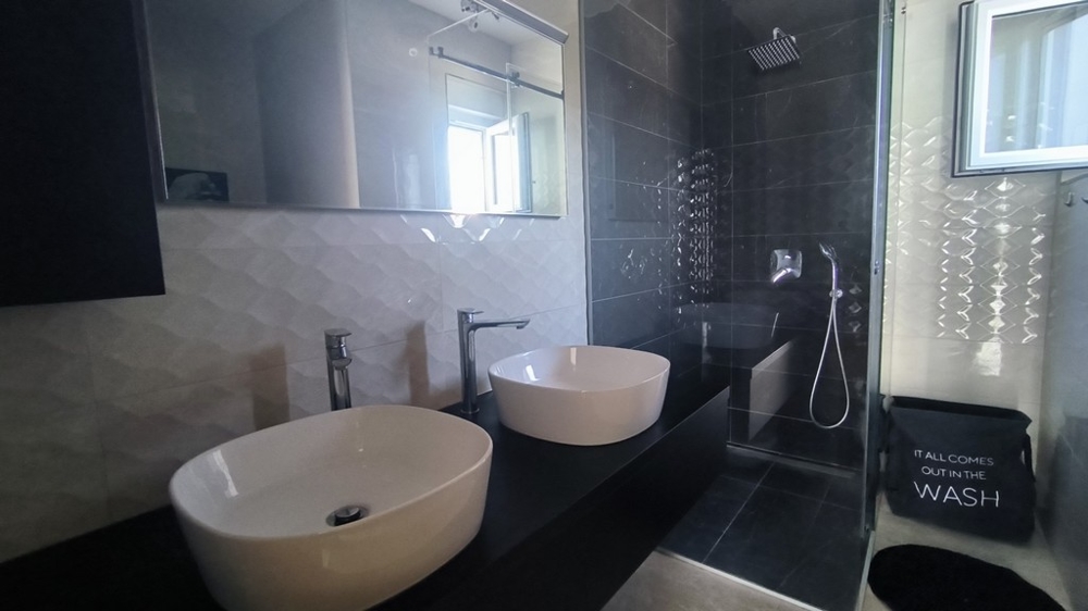 Modern fürdőszoba dupla mosdóval és esőzuhannyal.