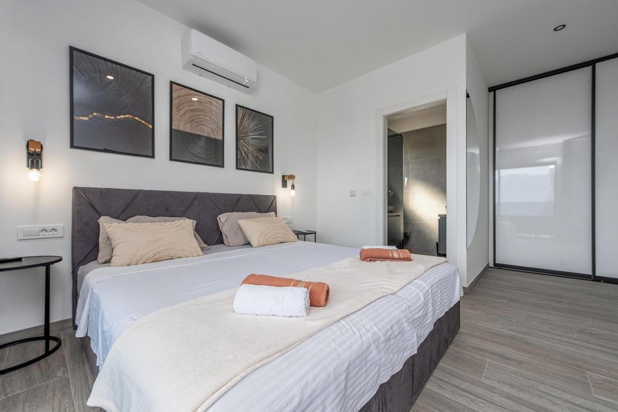 Hálószoba nagy ággyal, modern falfestményekkel és saját fürdőszobával.