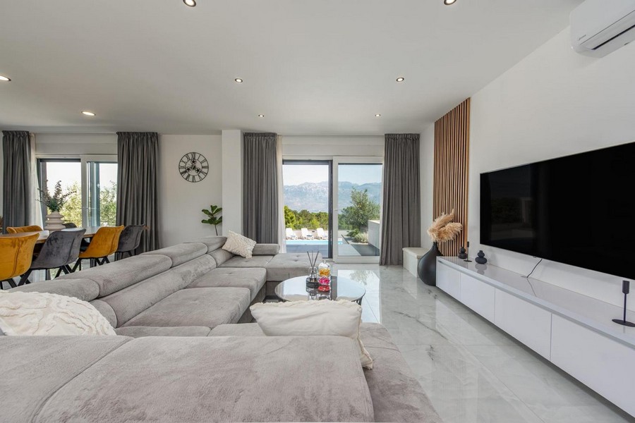 Nappali nagy panoráma ablakkal, kilátással a teraszra és a környező természetre.