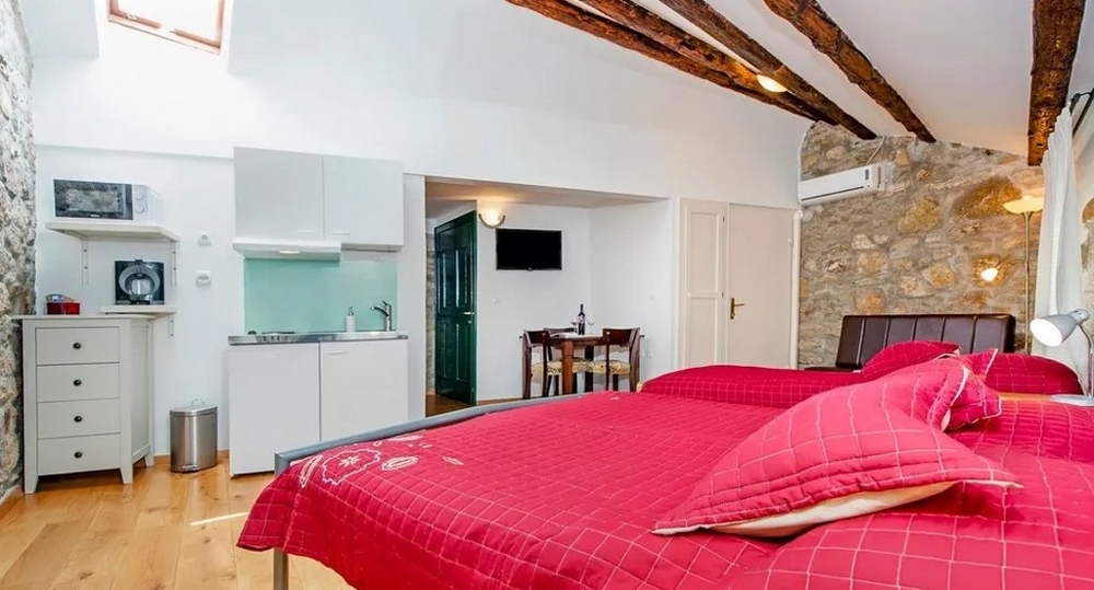 Stúdió kőfallal, kétszemélyes ággyal és konyhasarokkal