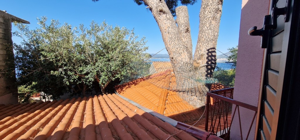Kilátás az erkélyről a cseréptetőre, a fákra és a tengerre
