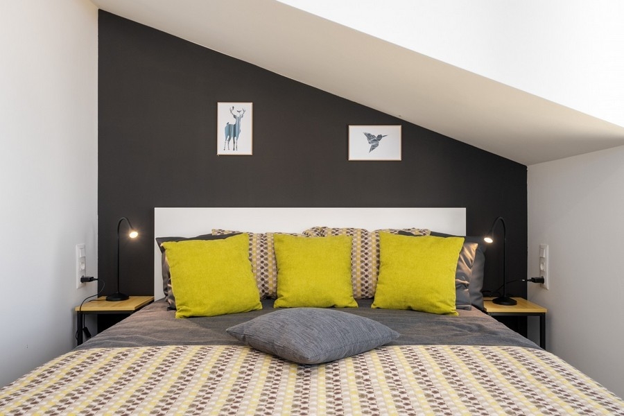 Tetőtéri hálószoba franciaággyal és sárga párnákkal