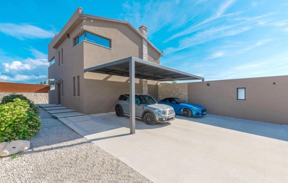 A villa előtt fedett kocsibeálló két autóval