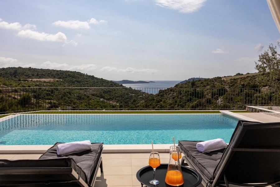 Végtelenített medence tengerre néző kilátással és napozóágyakkal