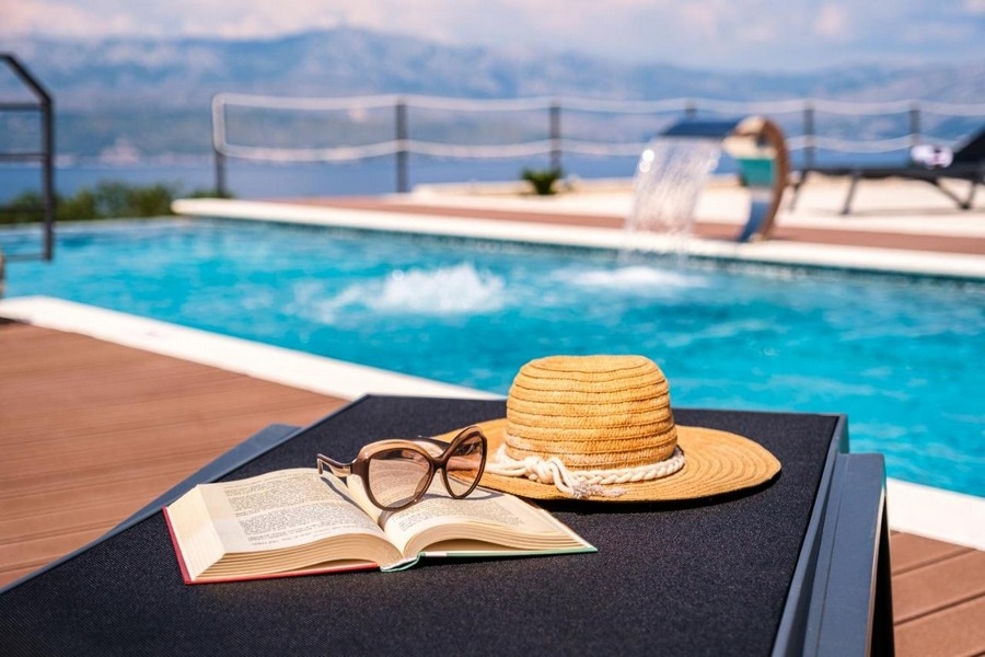 Részlet lövés a medence napozóágy, kalap, szemüveg és könyv