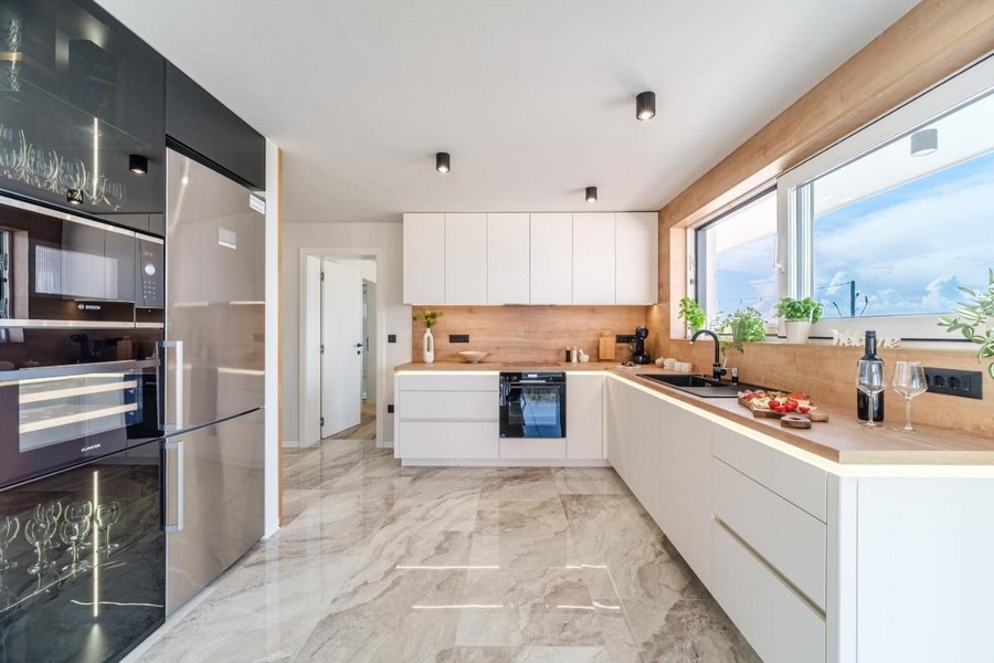 Világos felszerelt konyha modern gépekkel és márvány járólappal
