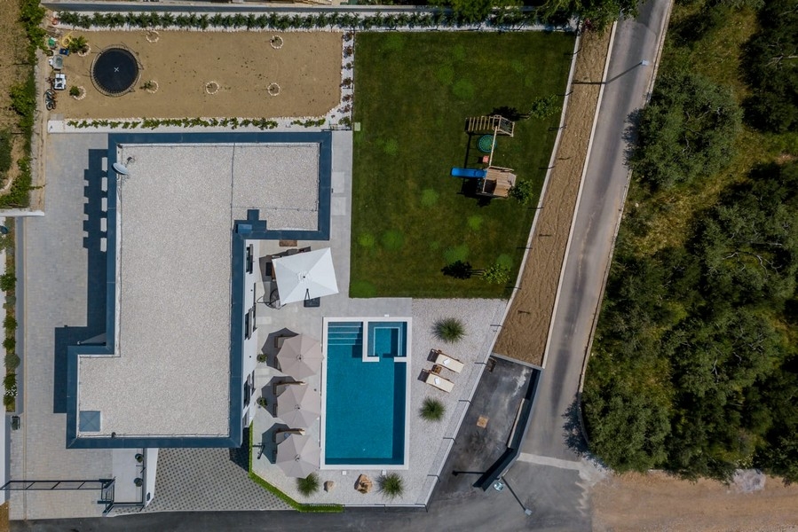 Az ingatlan medencével, kerttel és játszótérrel madártávlatból