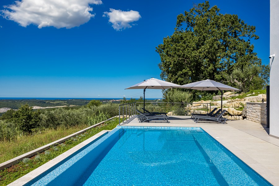 Tágas medenceterület napozóterasszal és kilátással a tengerre