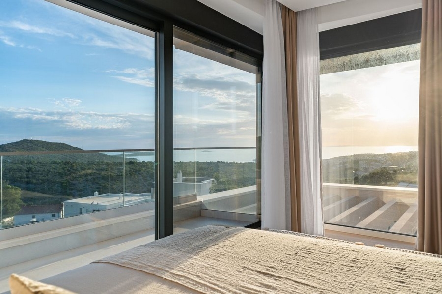 Hálószoba padlótól a mennyezetig érő ablakokkal és panorámás kilátással a tengerre