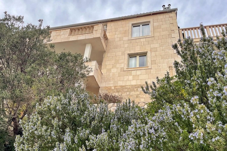 Természetes kőből készült házhomlokzat erkéllyel és kerttel