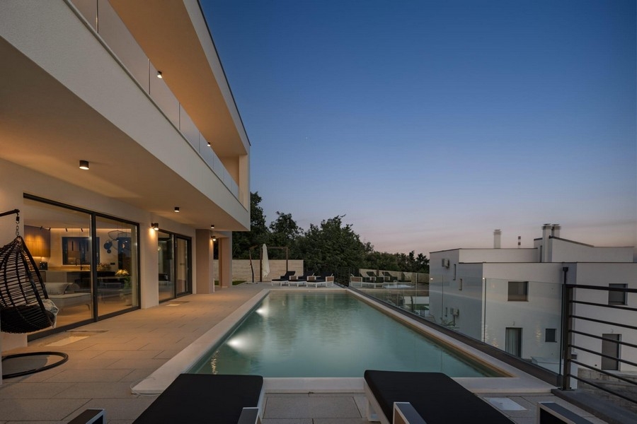 Modern villa végtelenített medencével és esti kilátással a tengerre