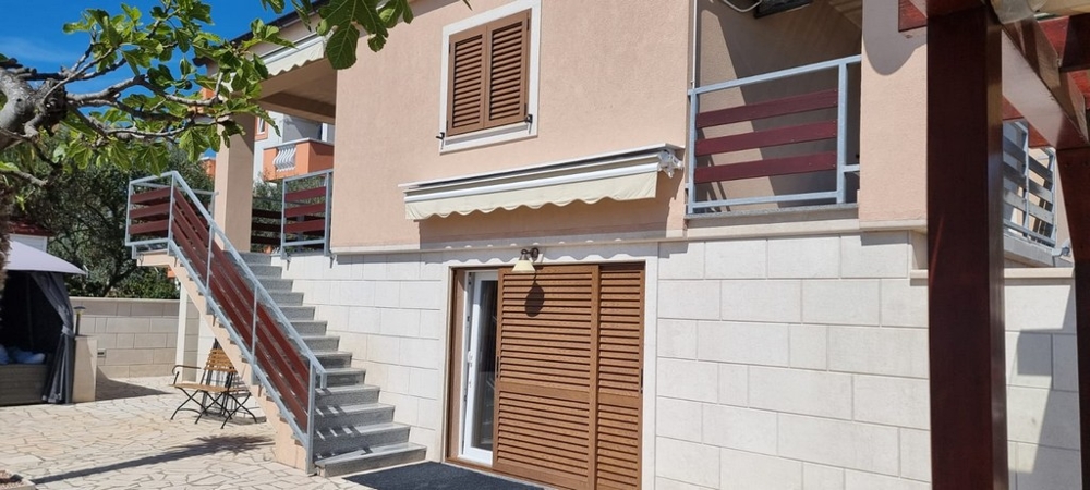 Házhomlokzat erkéllyel, napellenzőkkel és külön bejárattal a lakóegységekhez