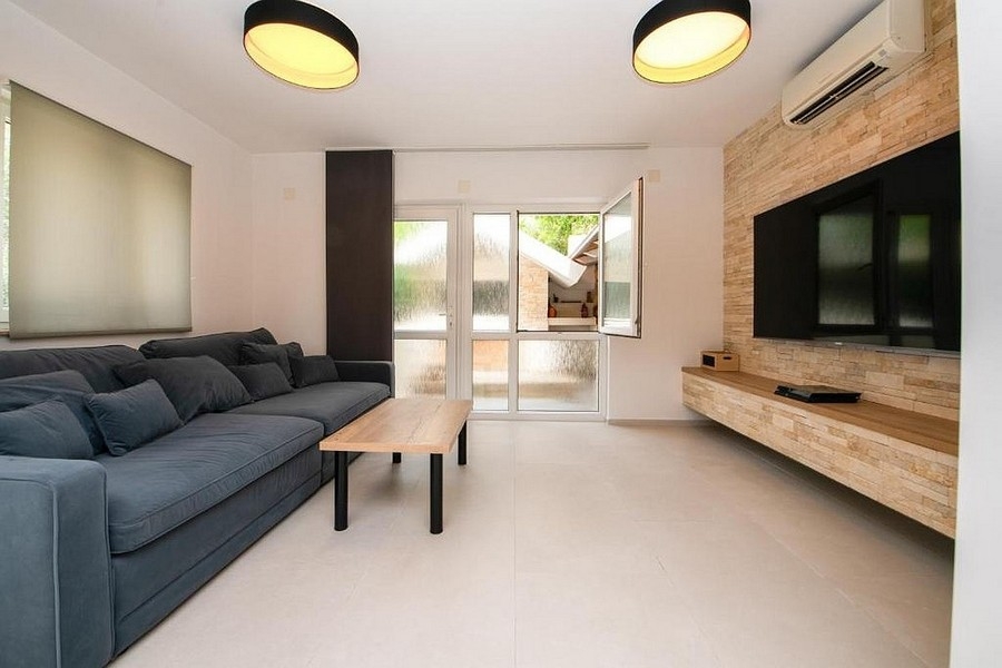 Modern nappali kanapéval, TV-fallal és kijárattal a teraszra