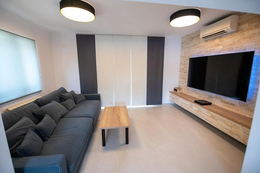 Nappali nagy TV-vel és modern falkialakítással